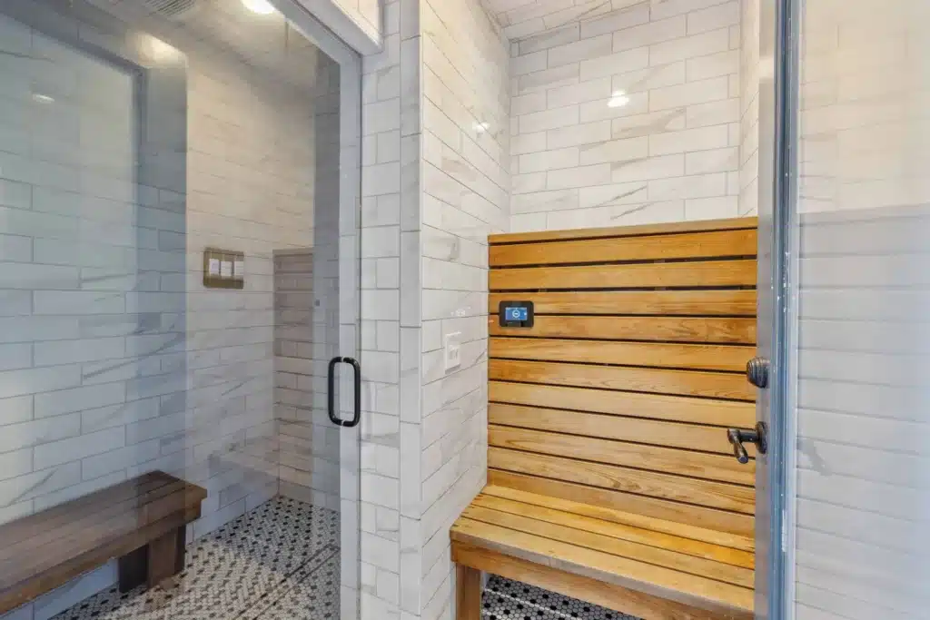 A modern sauna with wooden benches and digital control is adjacent to a tiled shower area separated by a glass door.